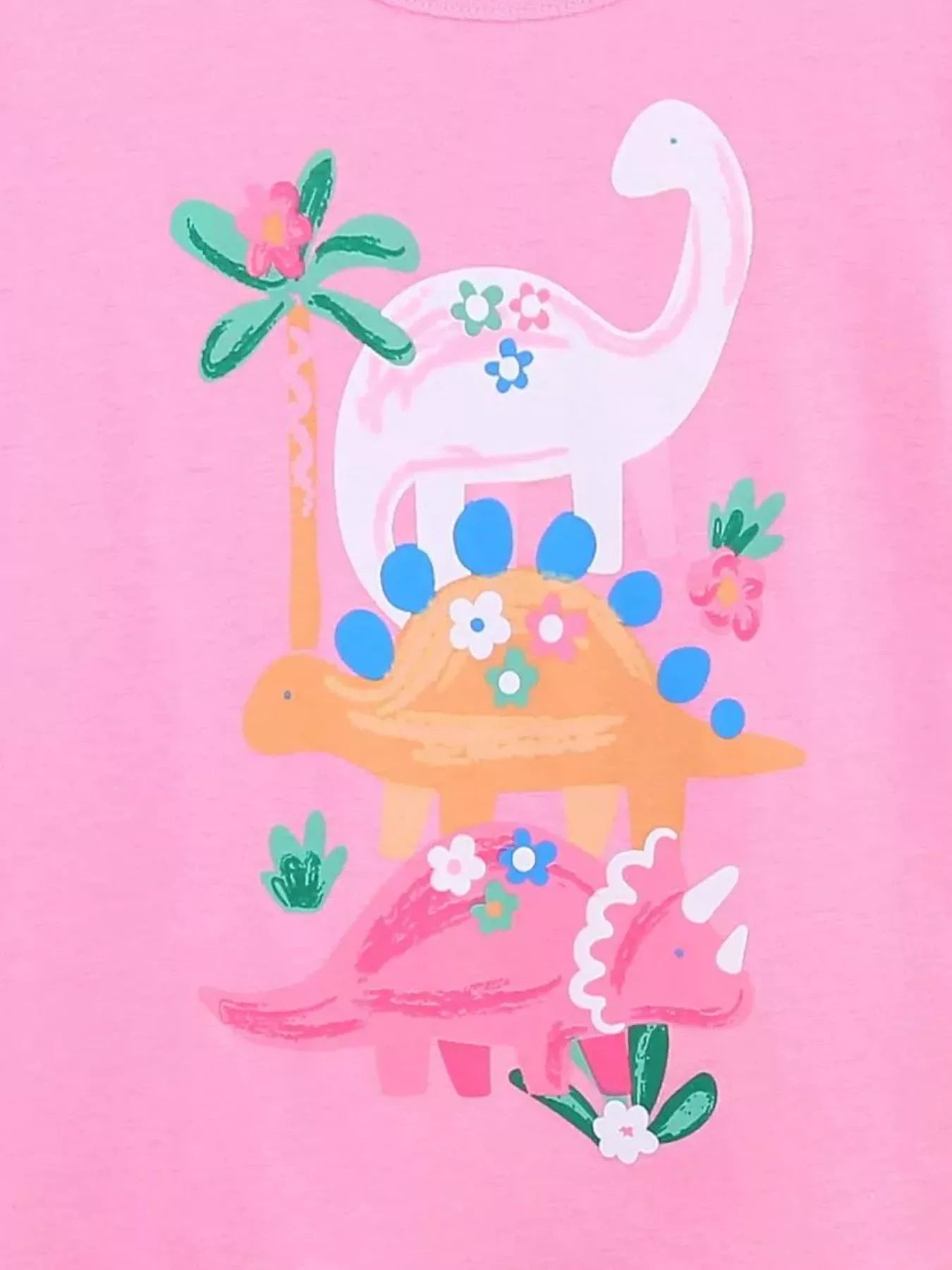 Close-up detail of the dinosaur print with flowers and a palm tree on pink fabric
