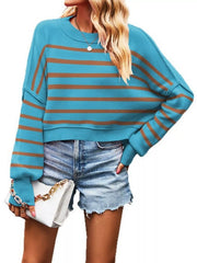 Front view of the turquoise sweater with brown stripes, crew neck, and dropped shoulders, holding a handbag.