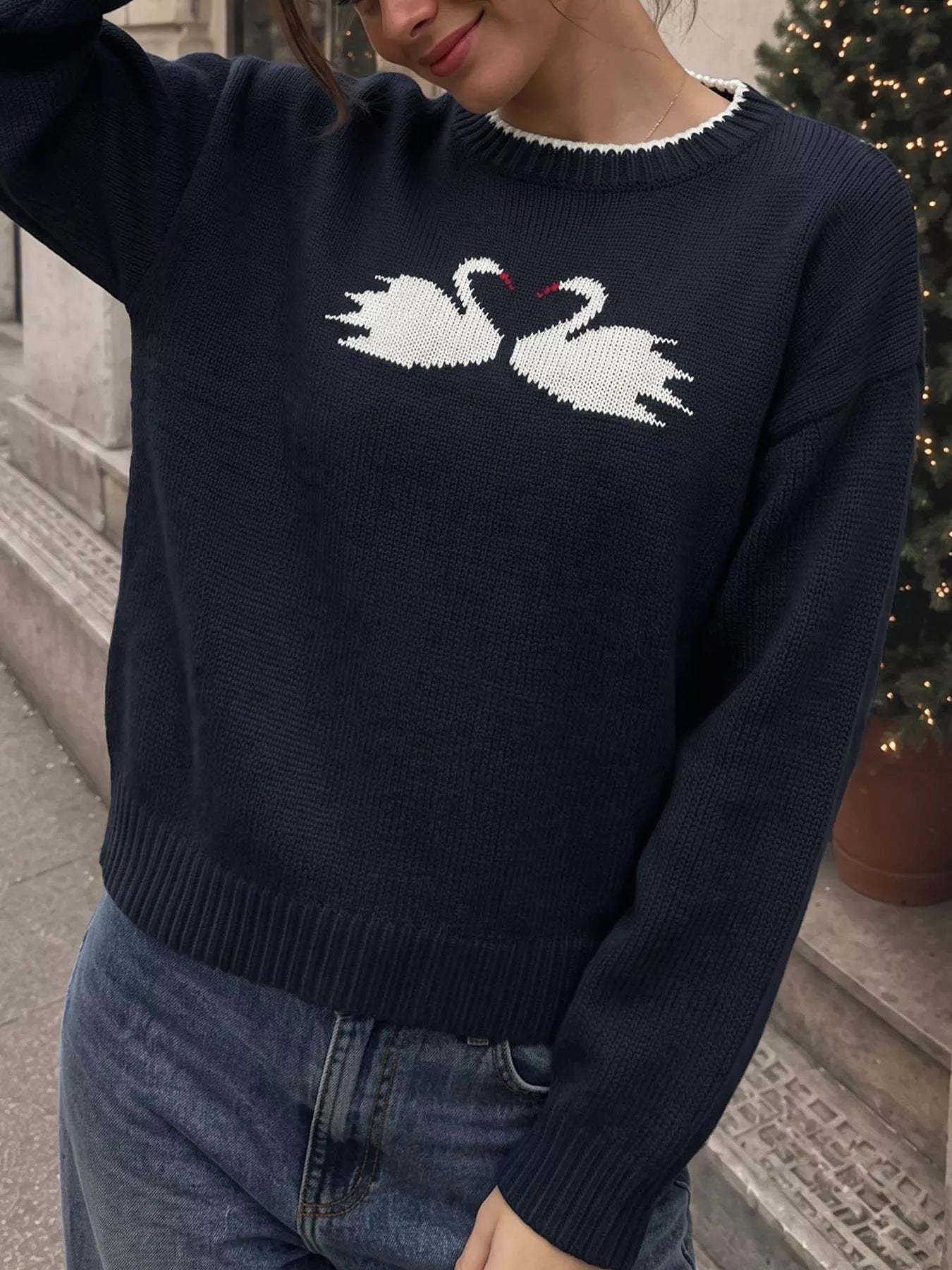 Front view of a navy sweater with facing white swans and dropped shoulder sleeves
