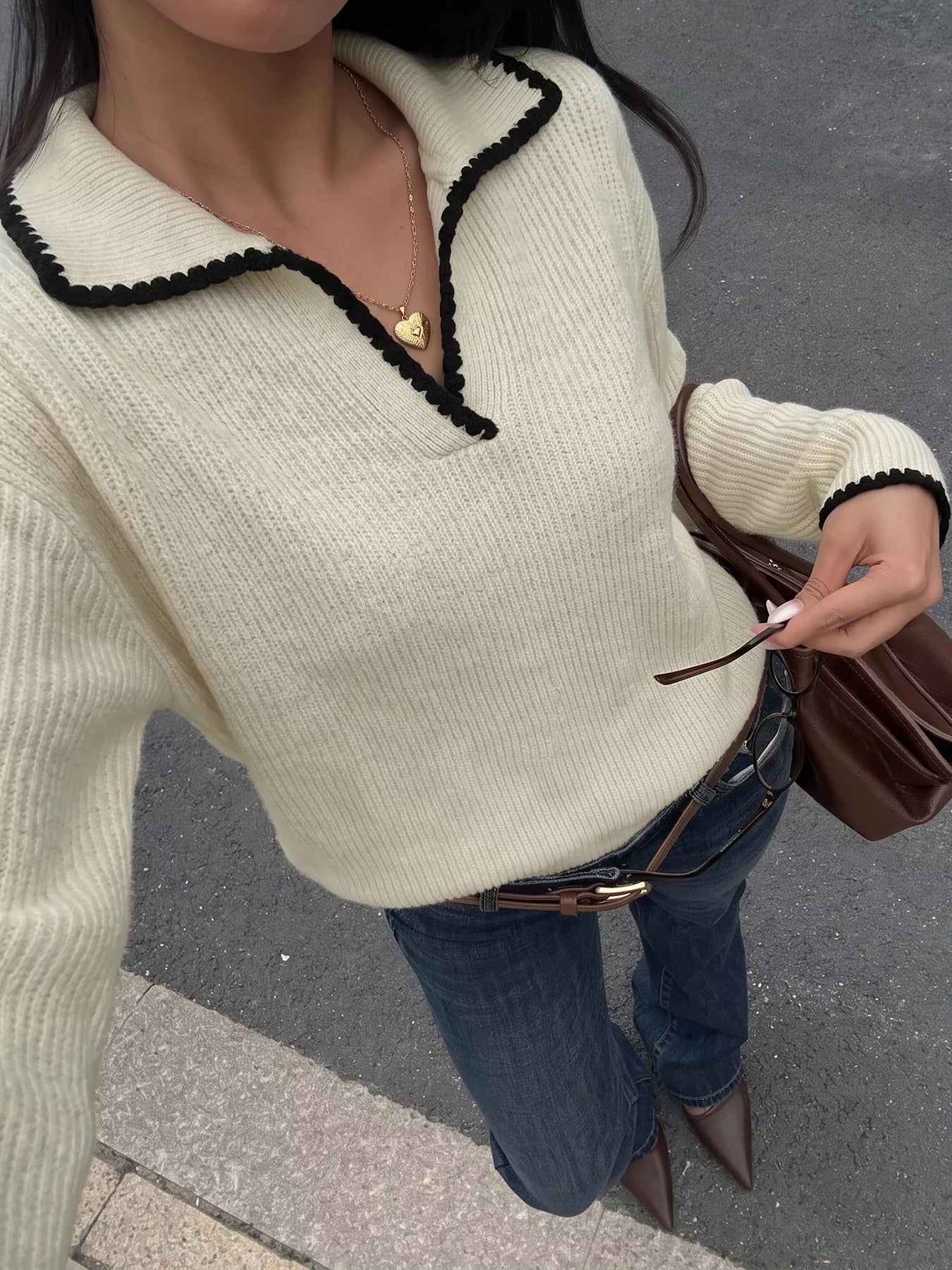 Front view of a cream ribbed sweater with black scalloped collar and long sleeves