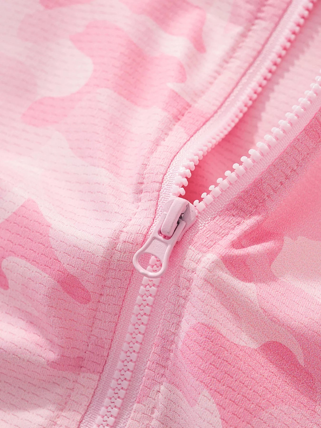 Close view of the pink zipper pull and blush pink camouflage fabric texture on the jacket
