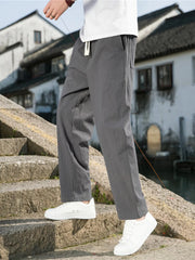 Men's dark gray loose-fit casual pants with a drawstring waist and pockets.