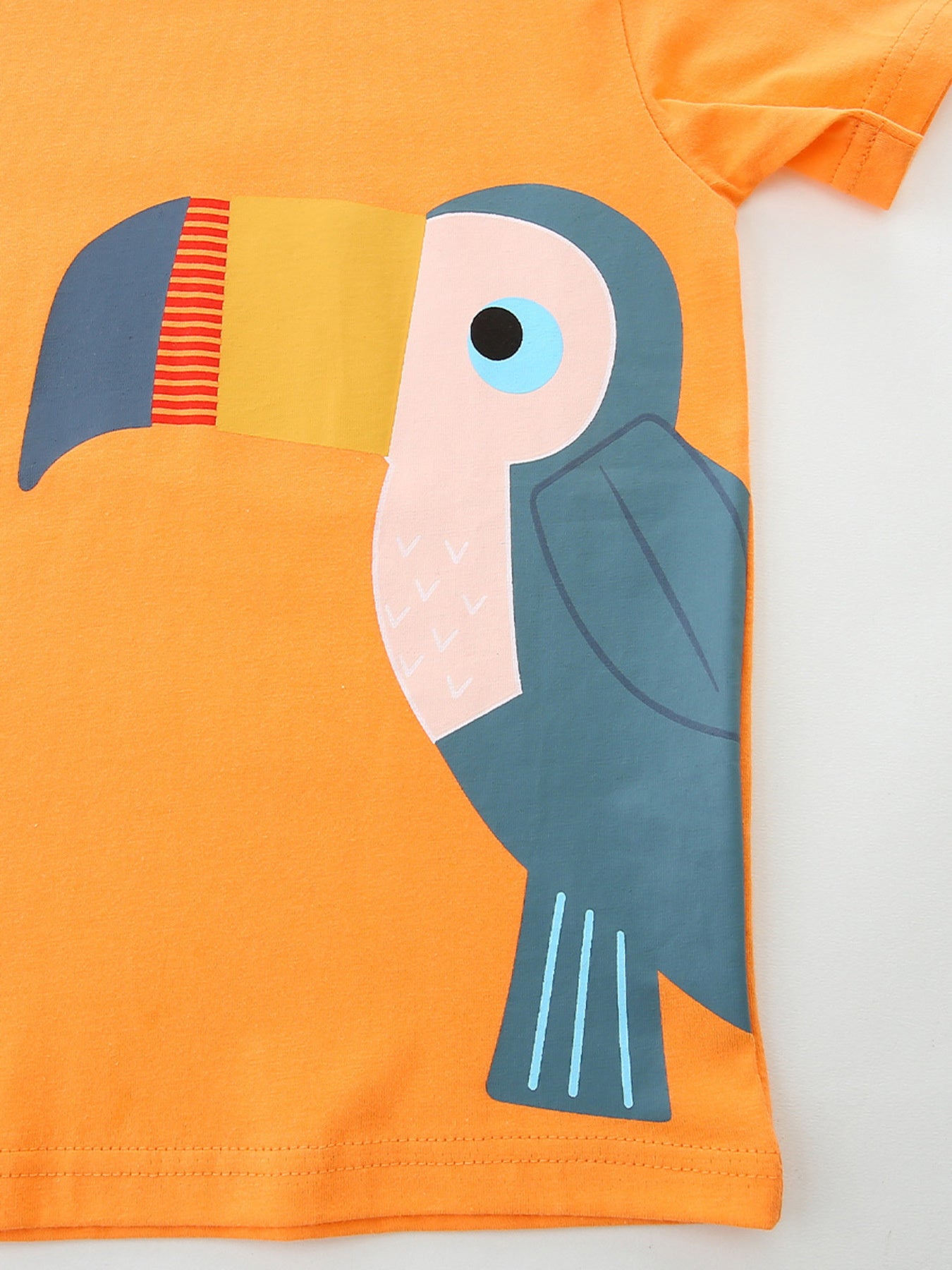 Close-up of large toucan graphic with yellow red and blue beak on orange tee