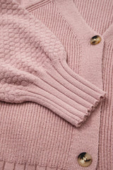 Flat lay close-up of the textured sleeve and ribbed cuff on a dusty pink cardigan