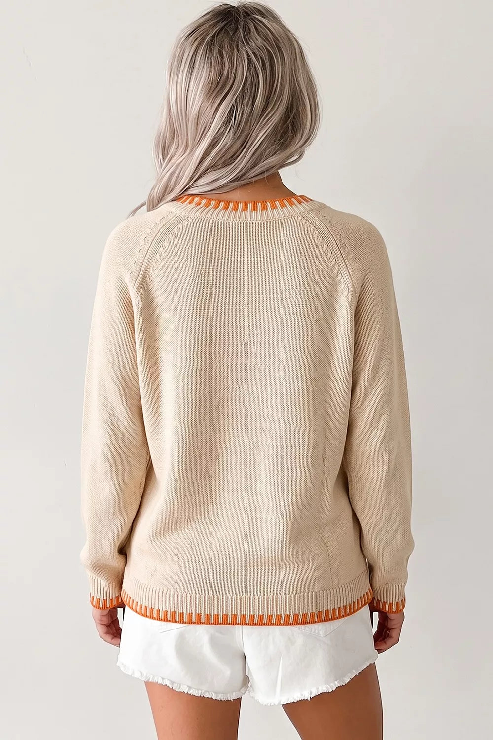 Back view of a plain beige long sleeve sweater with orange trim at the neckline and hem