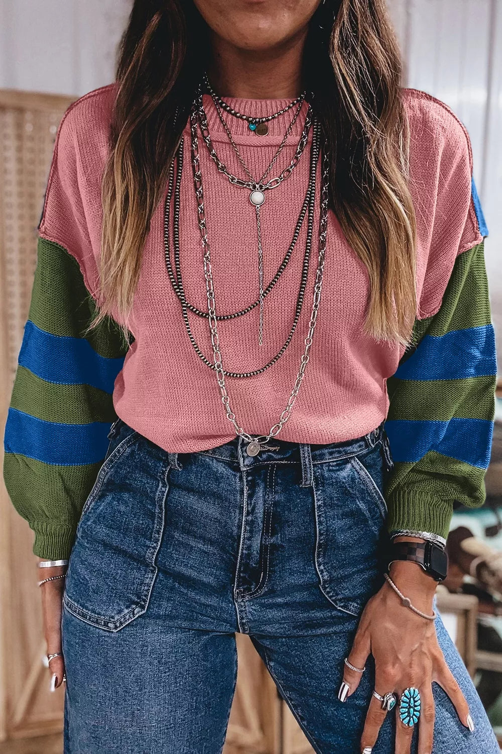 Front view of the pink colorblock sweater showing its striped green and blue sleeves