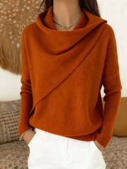 On-model front view of a burnt orange cowl neck sweater with a draped asymmetric collar and long sleeves