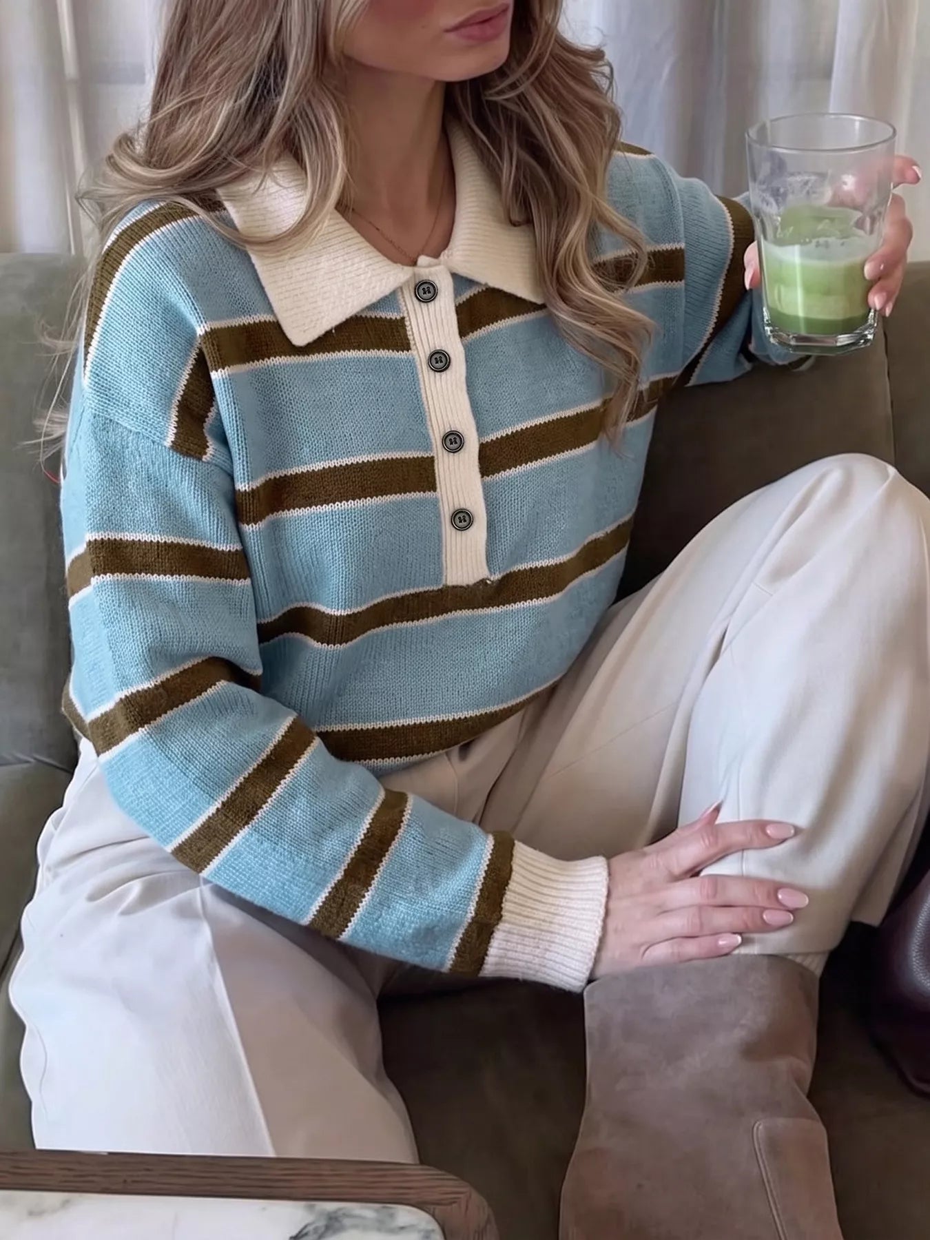 Seated front view of striped blue polo sweater with cream collar and button placket.
