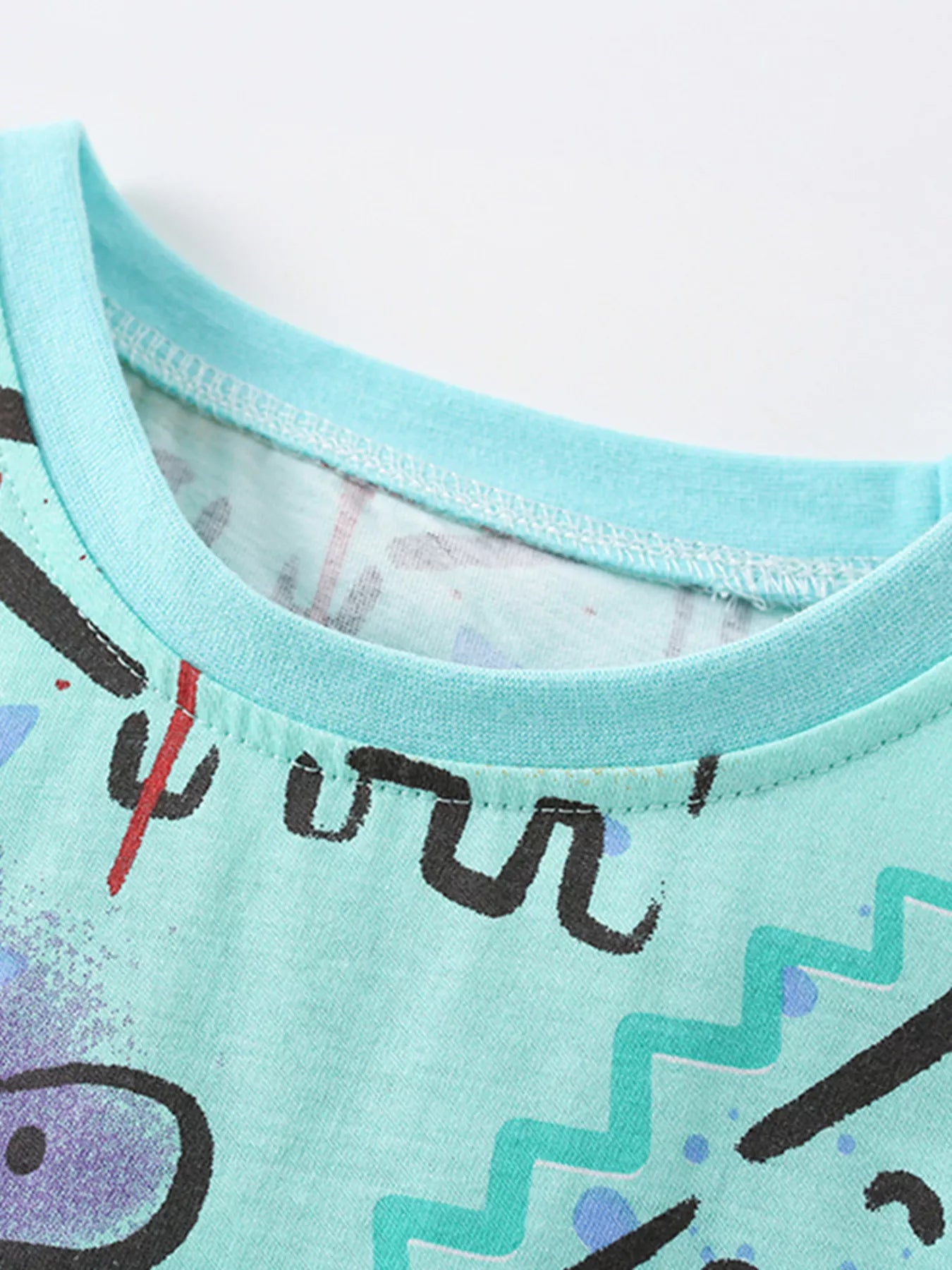 Close-up of mint crew neckline and stitching on multicolor children's dinosaur print t-shirt