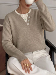 Khaki dropped shoulder sweater with button placket, model seated holding a cup