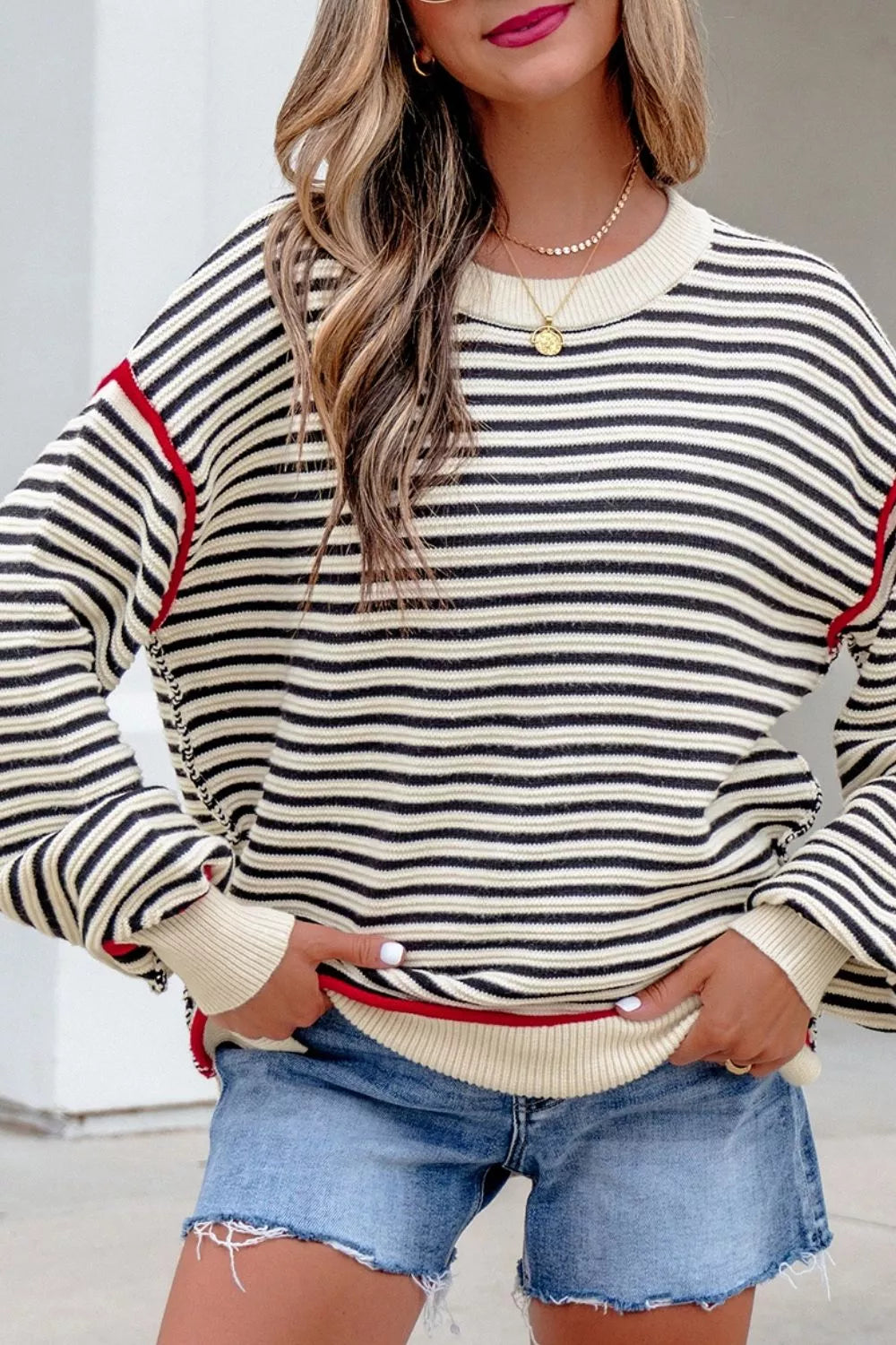 On-model front view of the striped oversized sweater with hands holding the ribbed hem