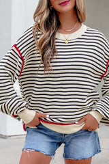 On-model front view of the striped oversized sweater with hands holding the ribbed hem