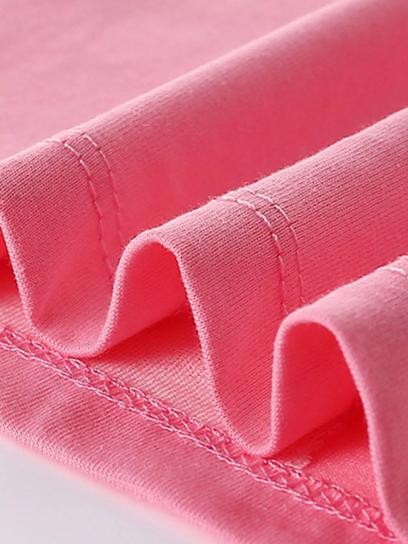 Close-up of the pink shirt hem showing neat stitching and soft folded fabric