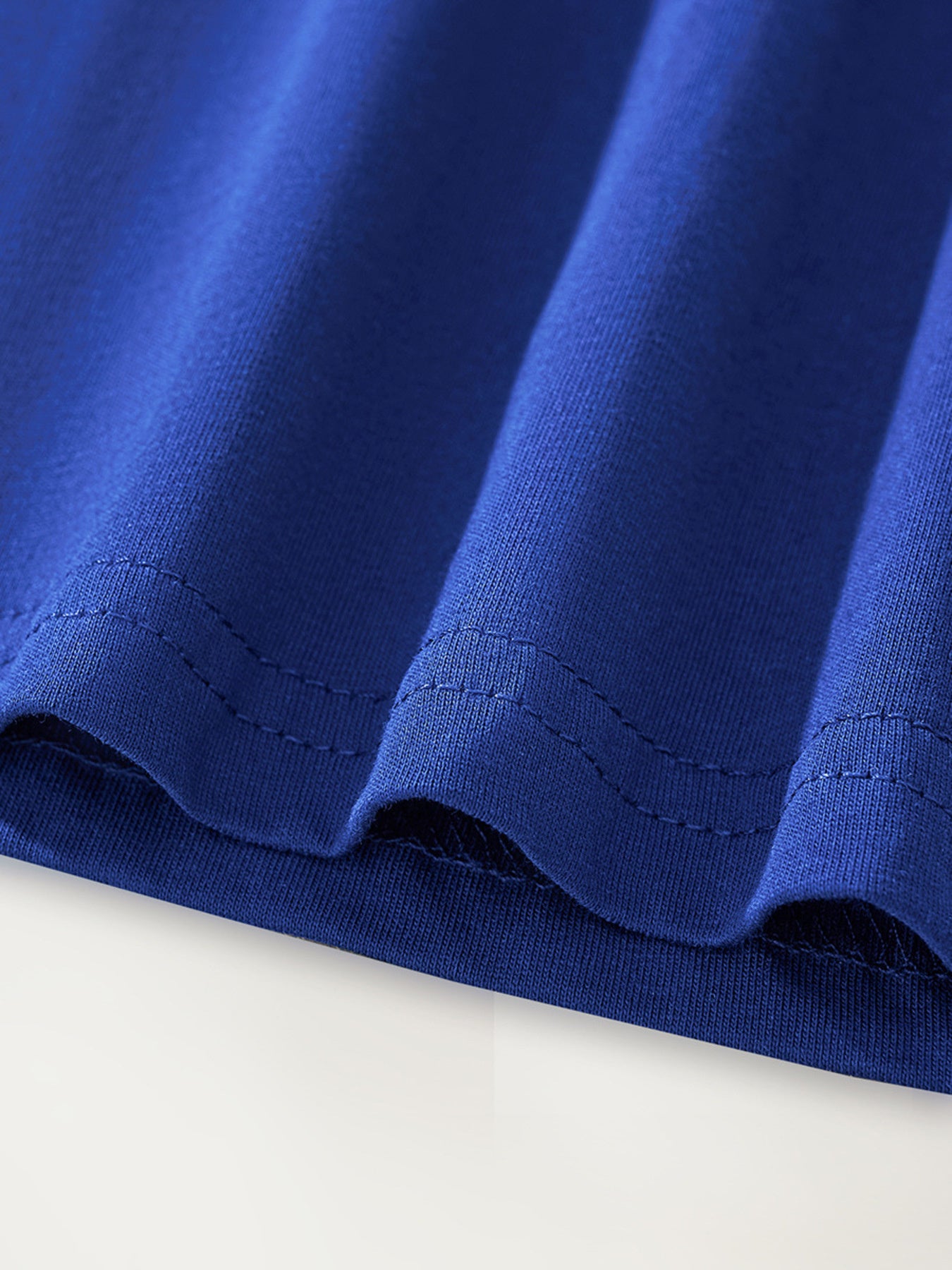 Close-up of the stitched hem and smooth navy fabric on the children's graphic tee
