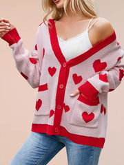 Pink knit cardigan with red hearts buttoned with hand in pocket