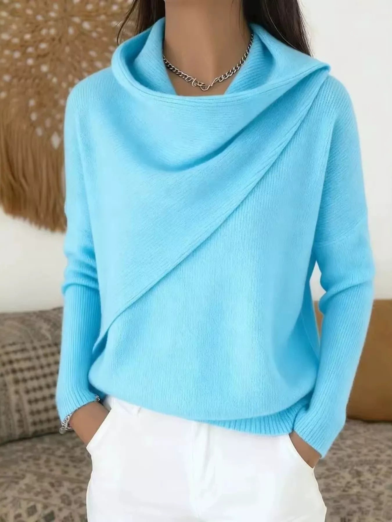 On-model front view of a light blue cowl neck sweater with a draped asymmetric collar and long sleeves