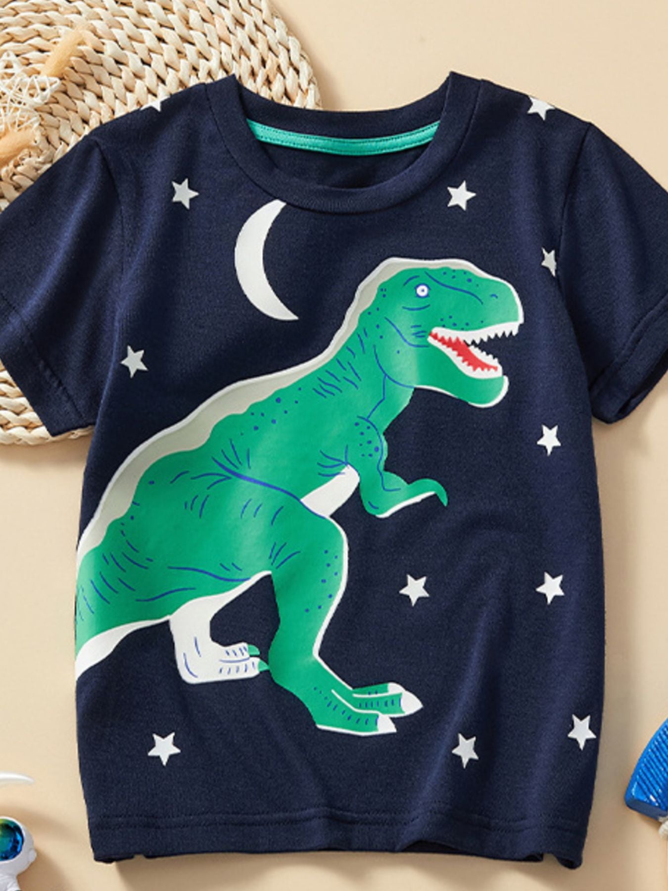 Flat lay front view of children's dark navy t-shirt with large green dinosaur and stars