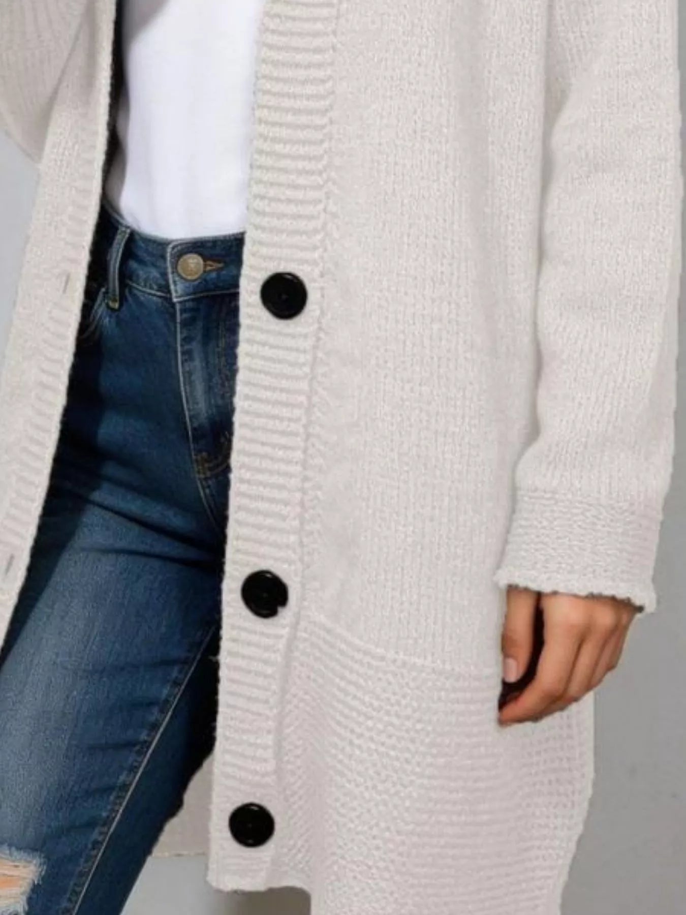 Close view of the cream hooded cardigan button placket and ribbed cuff