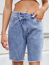 Women's asymmetrical denim shorts with raw hems and pockets.