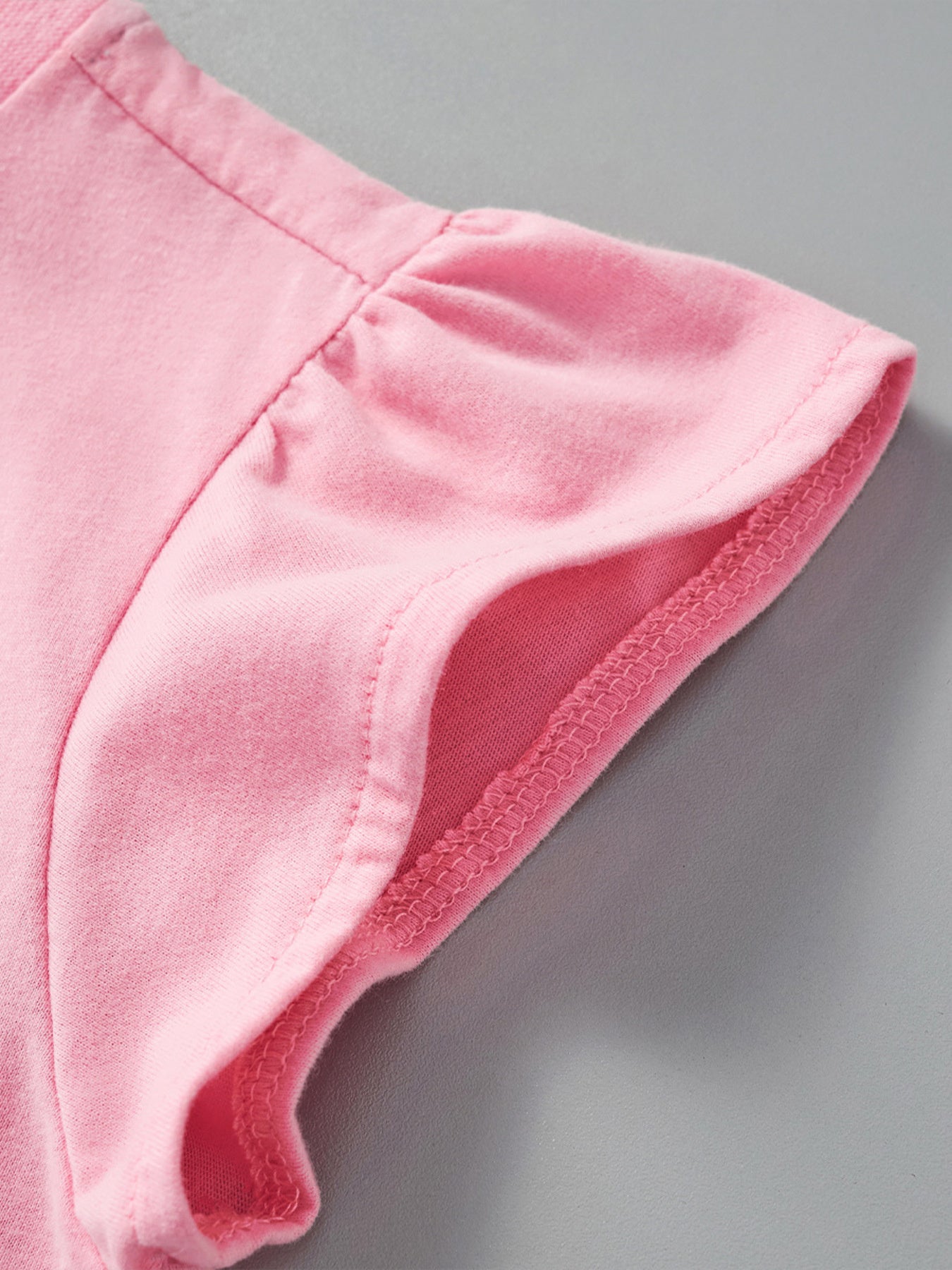 Close view of a gathered pink ruffle sleeve with neat stitching on children's unicorn tee