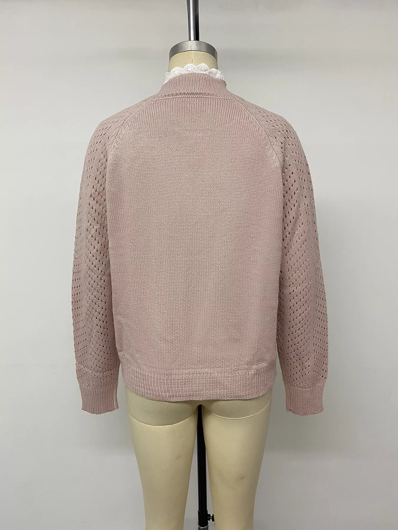 Back view on a mannequin of a pink sweater with openwork sleeves and ribbed hem