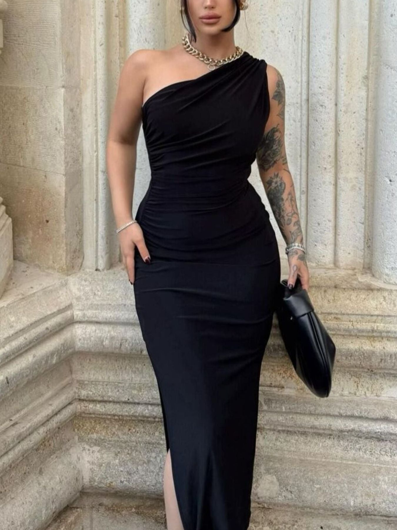 Model wearing black one shoulder ruched bodycon slit dress, front view with slit visible