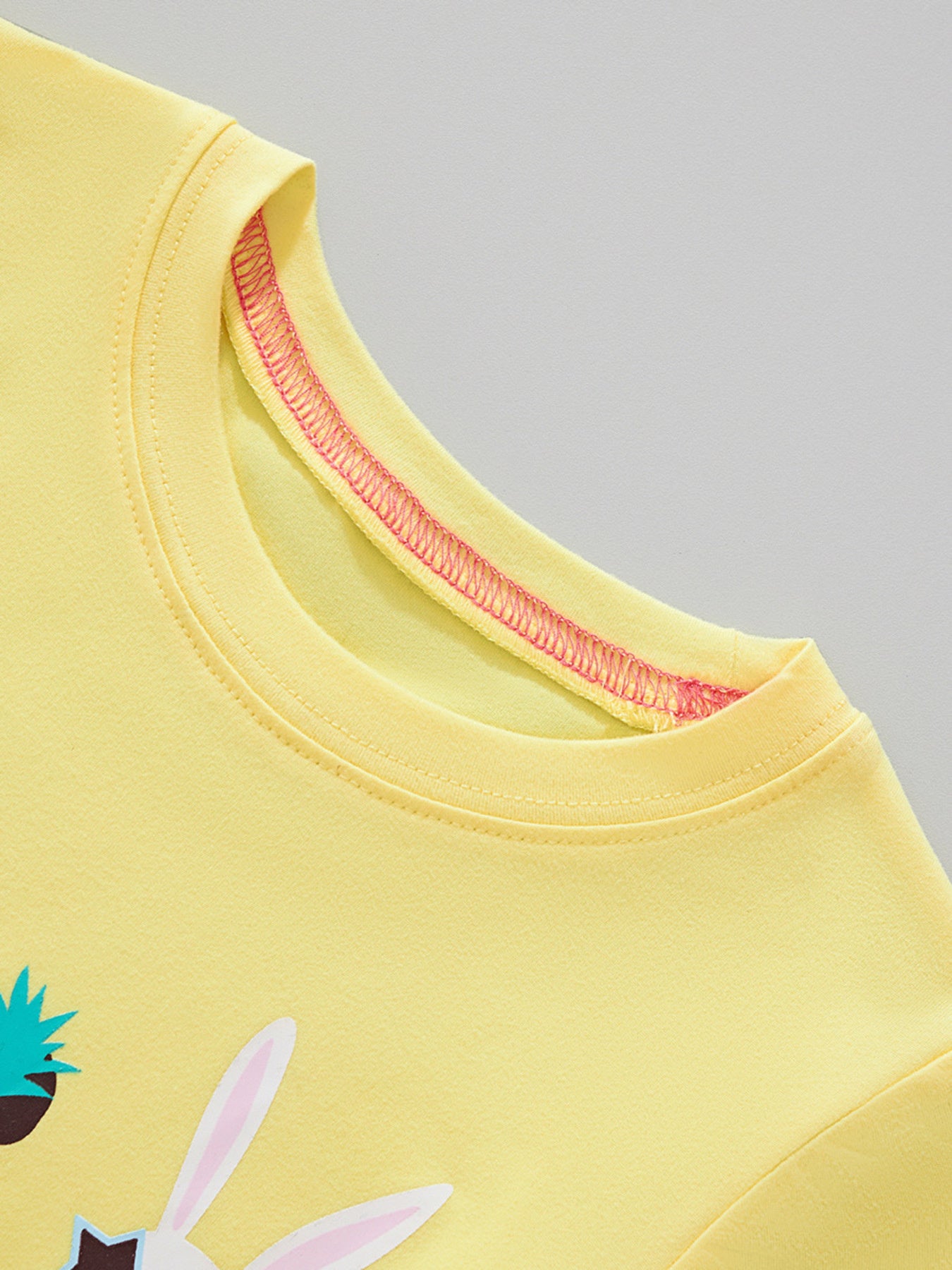 Close view of the round neckline with pink inner stitching on the yellow children's t-shirt
