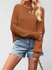 Front view of a camel crew neck dropped shoulder sweater with ribbed cuffs worn with denim shorts.