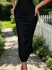 Close view of black ruched tube bodycon midi dress skirt showing ruched fabric