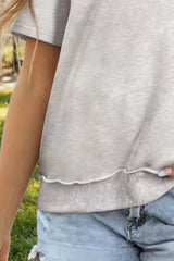 Close-up of a casual round-neck short-sleeve T-shirt showing its gray fabric and scalloped hem detail.