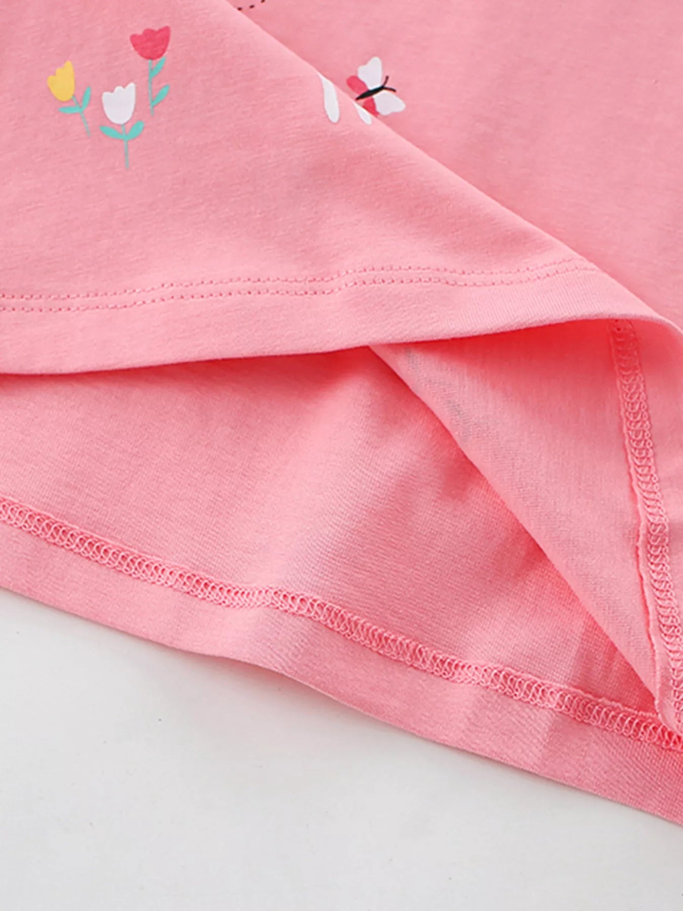 Close view of the stitched bottom hem and small tulip prints on the blush pink T-shirt