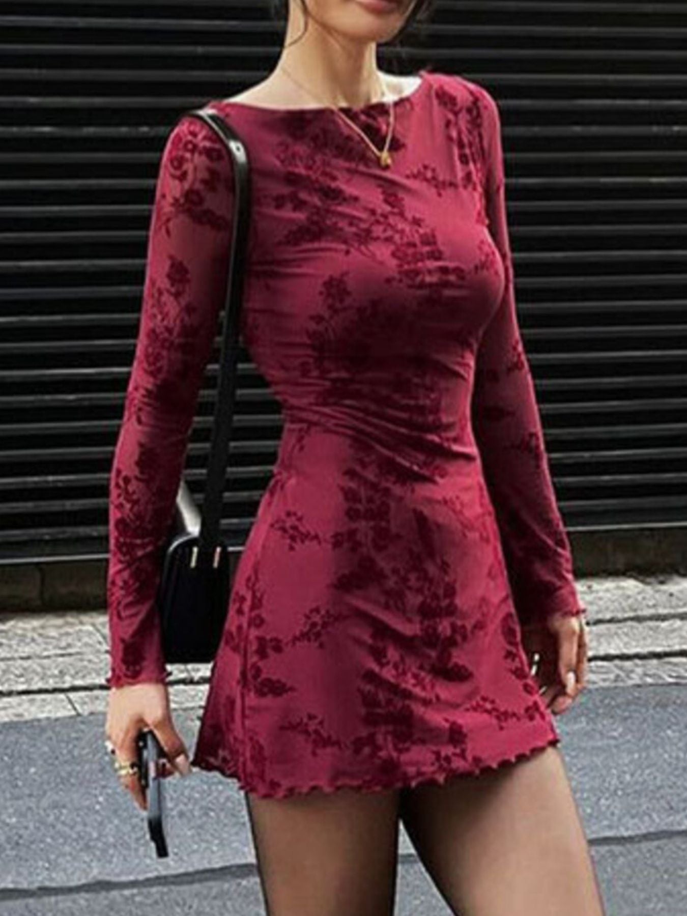 Burgundy floral long sleeve bodycon mini dress with sheer sleeves, three quarter view walking outdoors