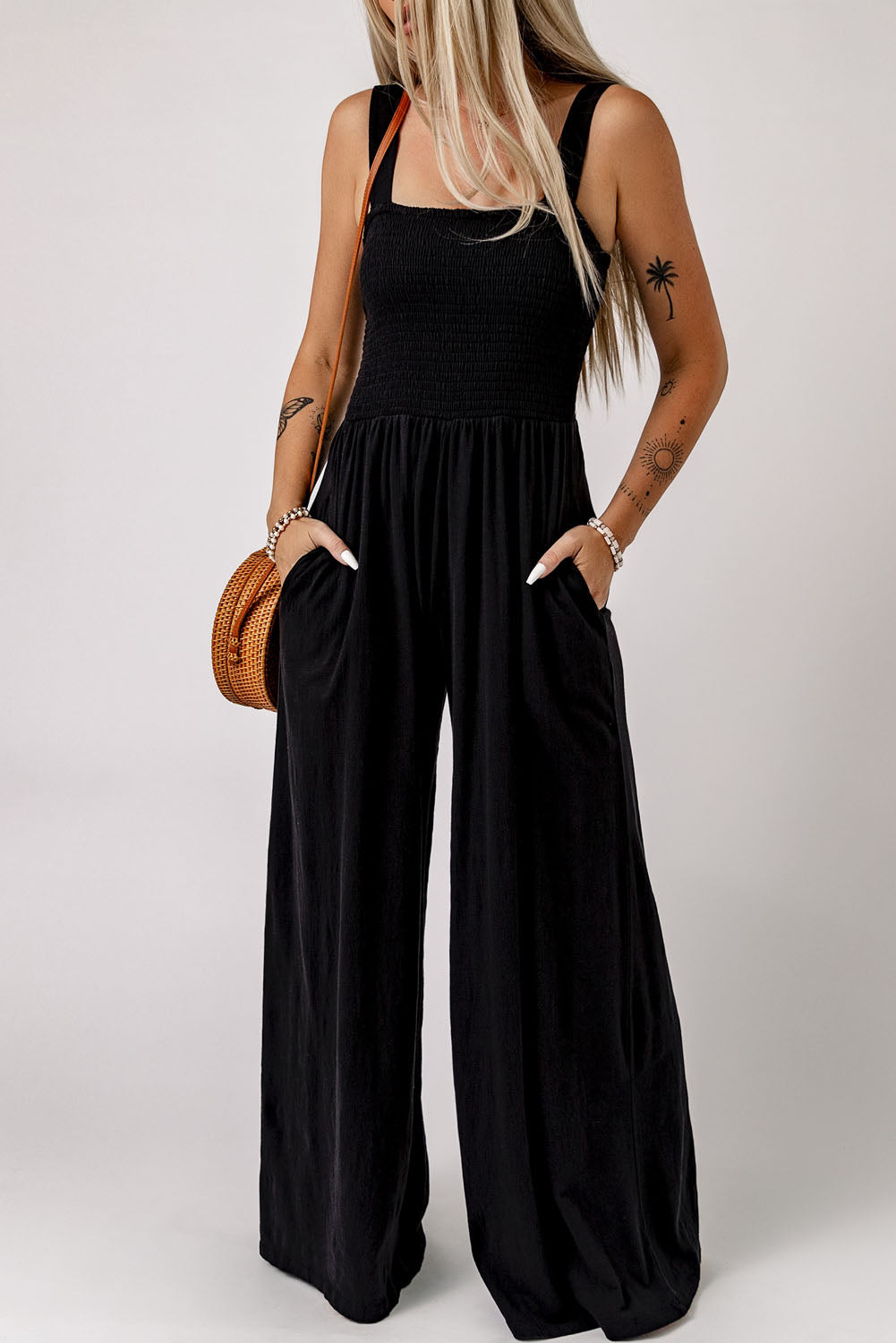 Women's smocked square-neck jumpsuit with sleeveless styling, wide legs, and pockets.
