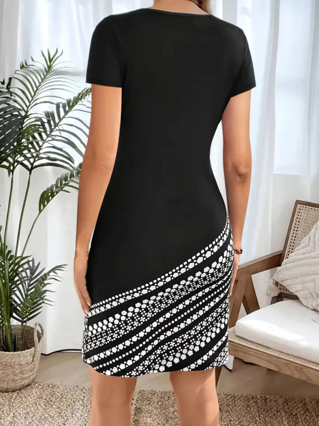 Black round neck bodycon mini dress with white geometric diagonal skirt panel, back view on model