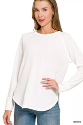 White women's waffle-knit long-sleeve top with raglan sleeves and a rounded hem, modeled with jeans