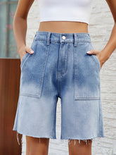 Women's light blue denim shorts with buttons, raw hems, and pockets.