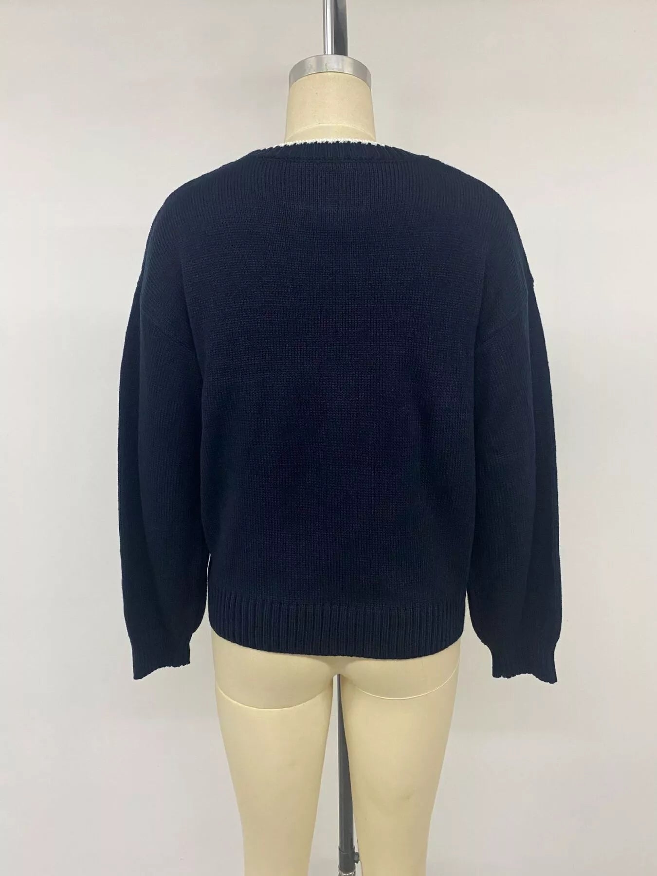 Back view on a mannequin of a plain navy sweater with ribbed hem and cuffs