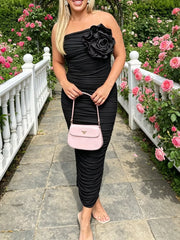 Front view of black ruched tube bodycon midi dress with large flower detail outdoors