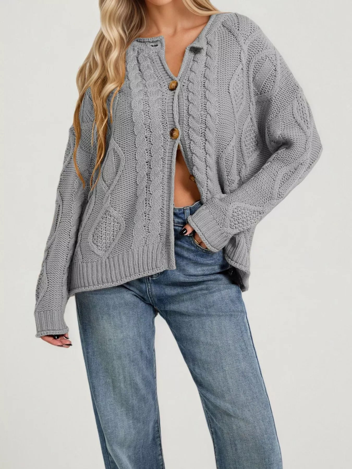Front view of gray cable knit button down cardigan with brown buttons and blue jeans