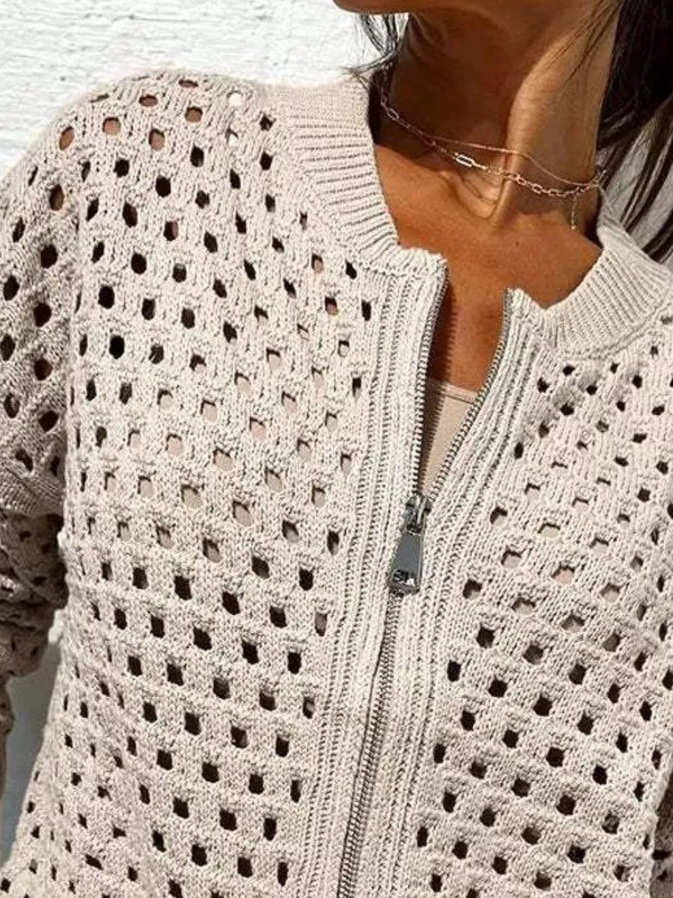 Close up of the pale beige crochet cardigan upper zip and openwork pattern