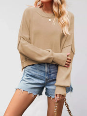Front view of a khaki crew neck dropped shoulder sweater with ribbed cuffs worn with denim shorts.