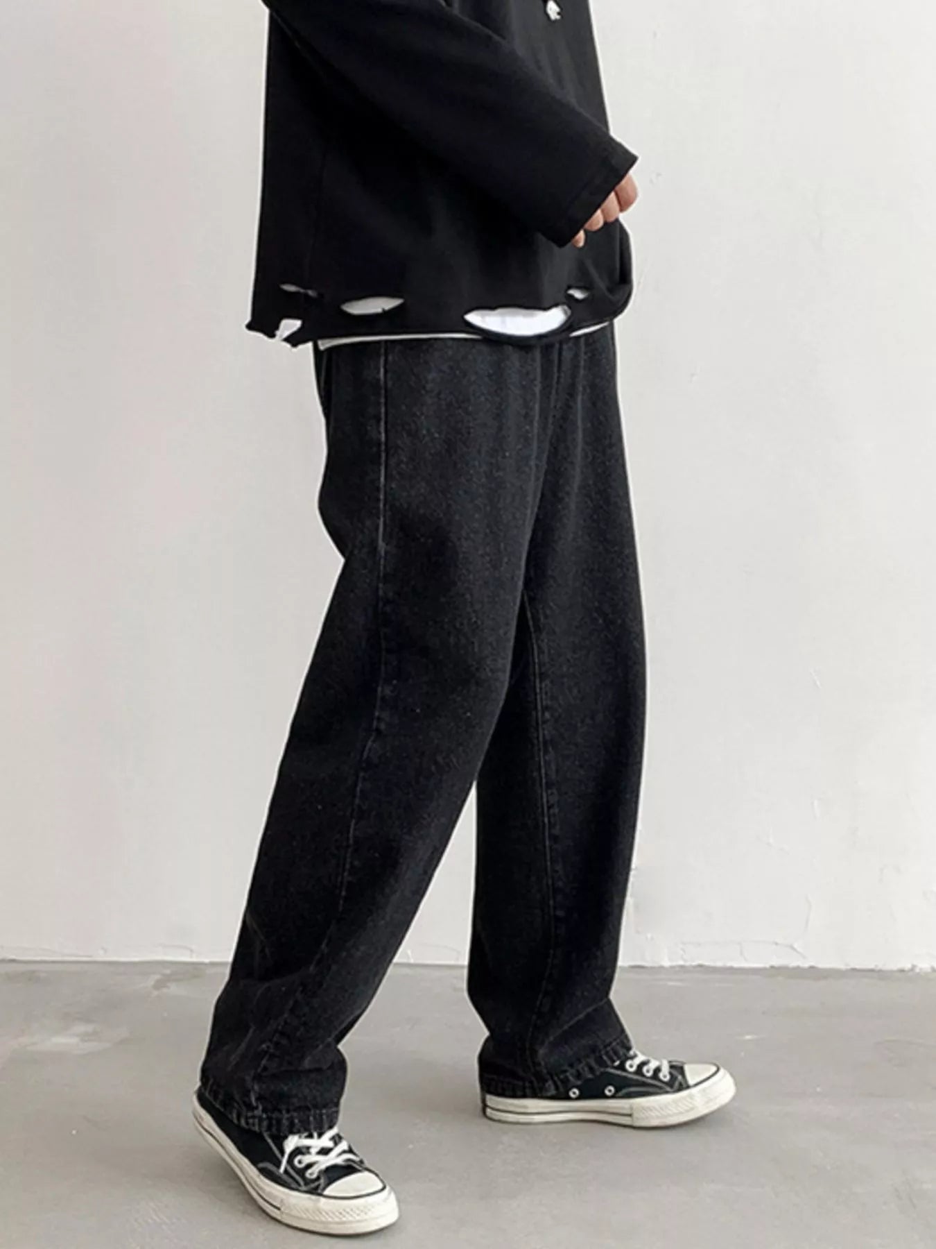 Men's Black loose fit wash jeans on model, side view while walking.
