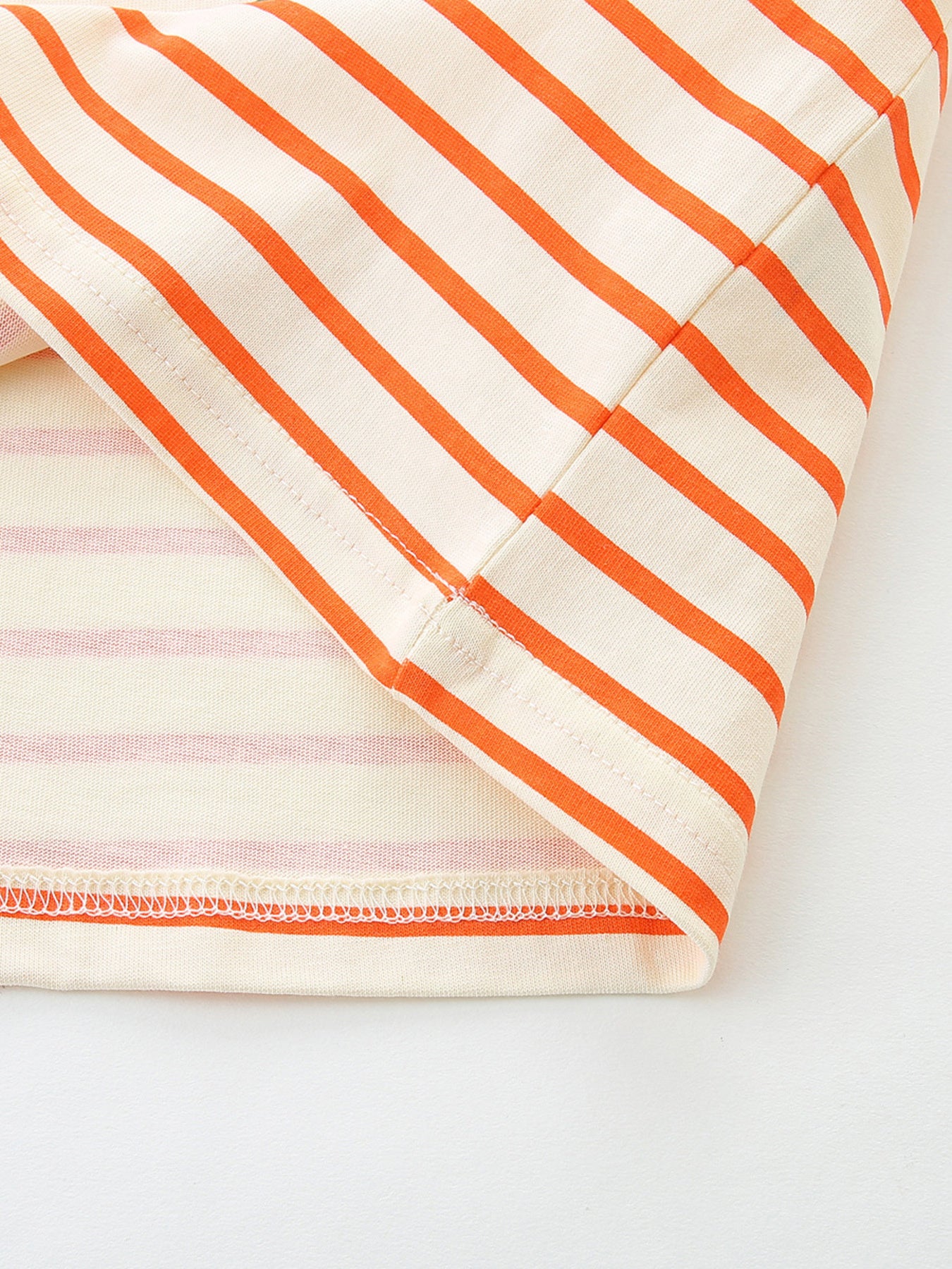 Close-up of the striped hem and stitching on the orange and white children's ruffle sleeve tee
