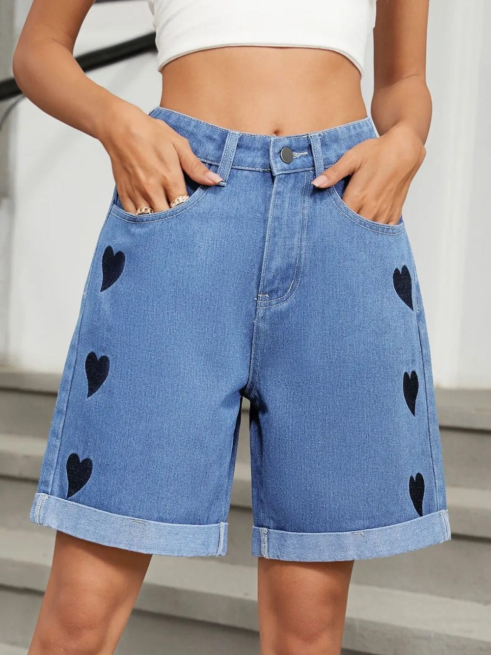 Women's heart-pattern denim shorts with rolled hems and pockets.