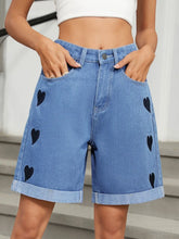 Women's heart-pattern denim shorts with rolled hems and pockets.