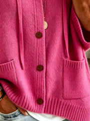 Detail view of the fuchsia pink cardigan showing brown buttons, patch pockets and ribbed hem