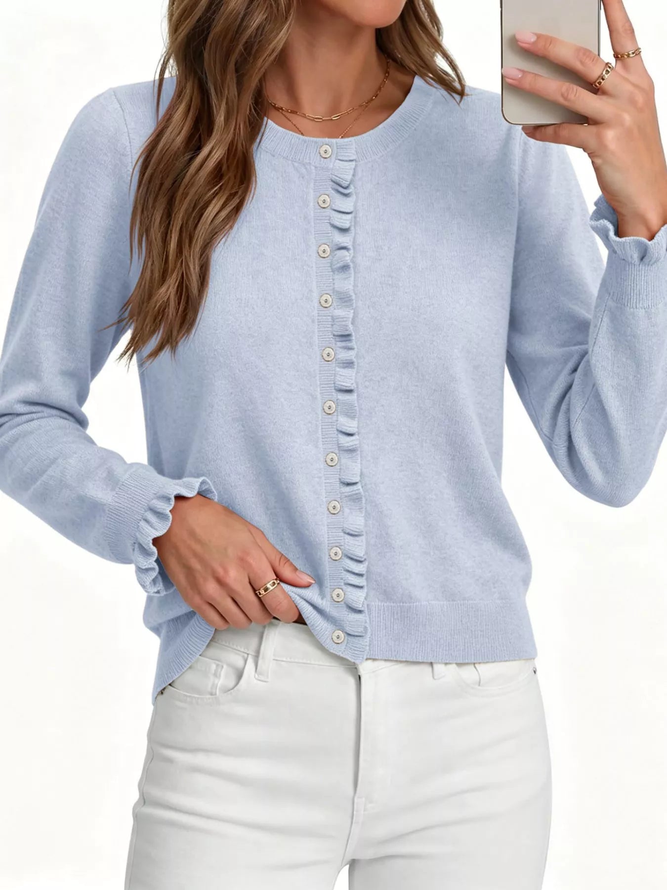 Close front view of light blue ruffle trimmed button down cardigan with white jeans on white background