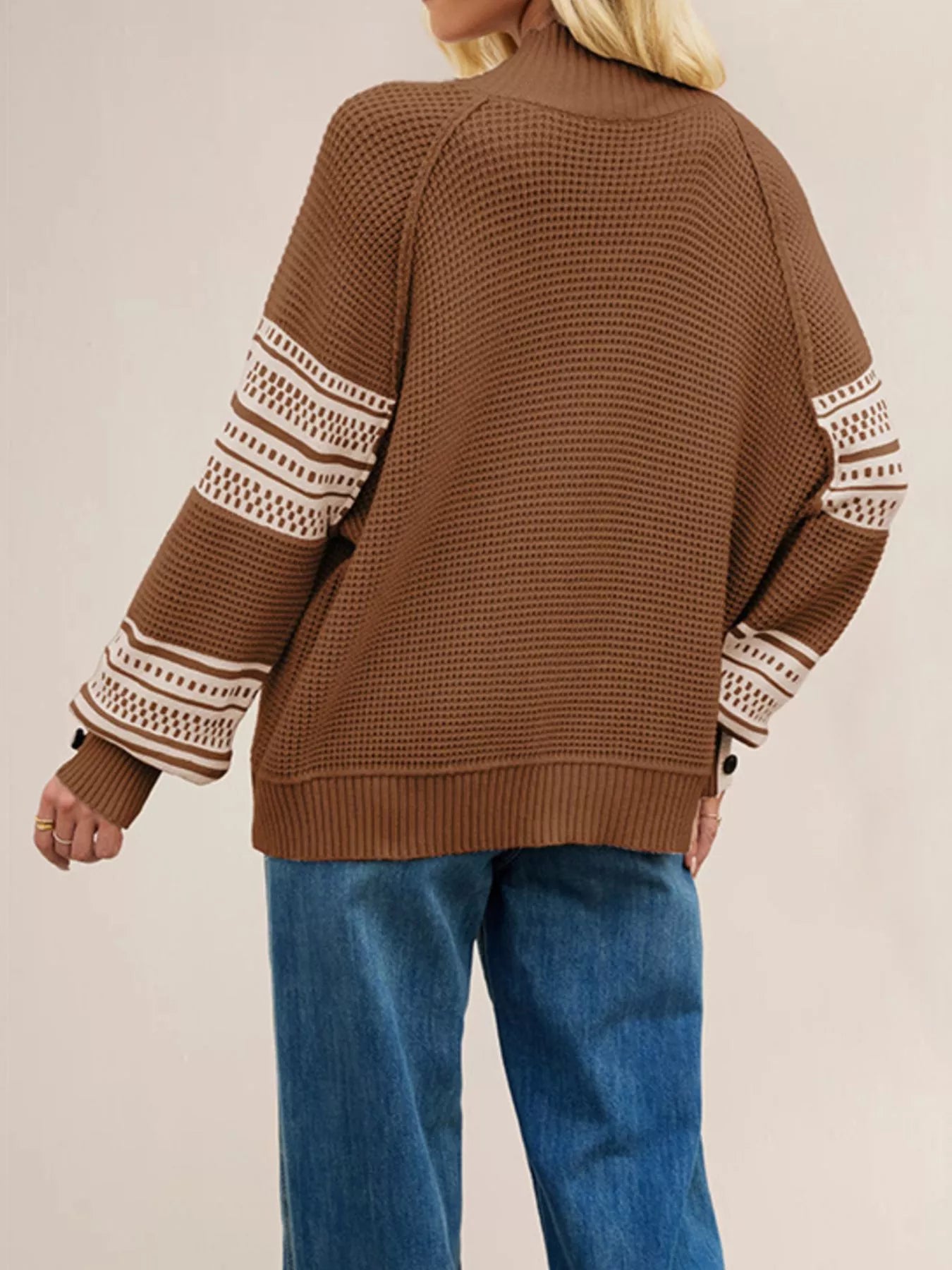 Back view of the brown waffle knit sweater with cream patterned sleeves and ribbed hem.