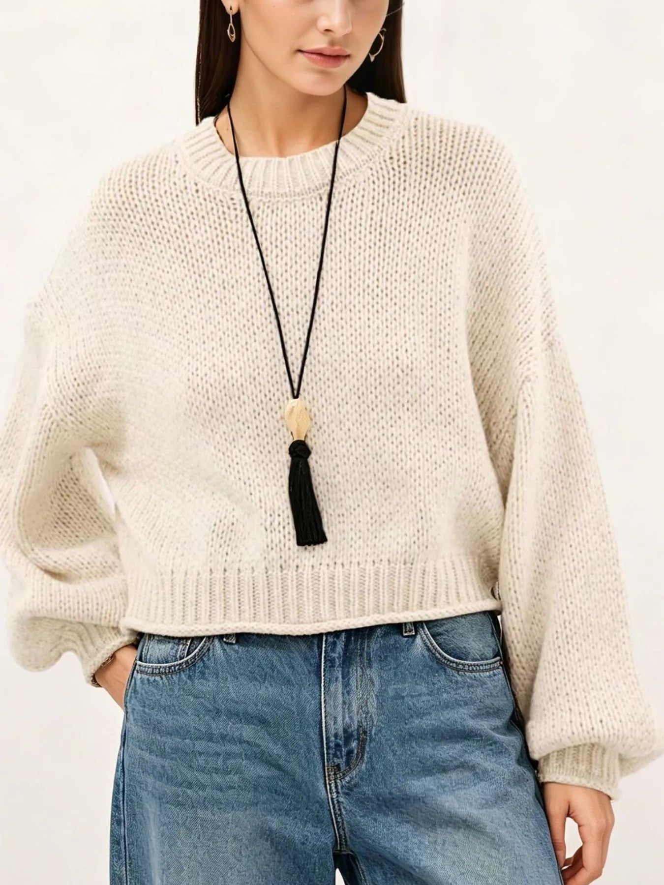 Close on-model front view of a cream oversized chunky knit sweater with ribbed hem