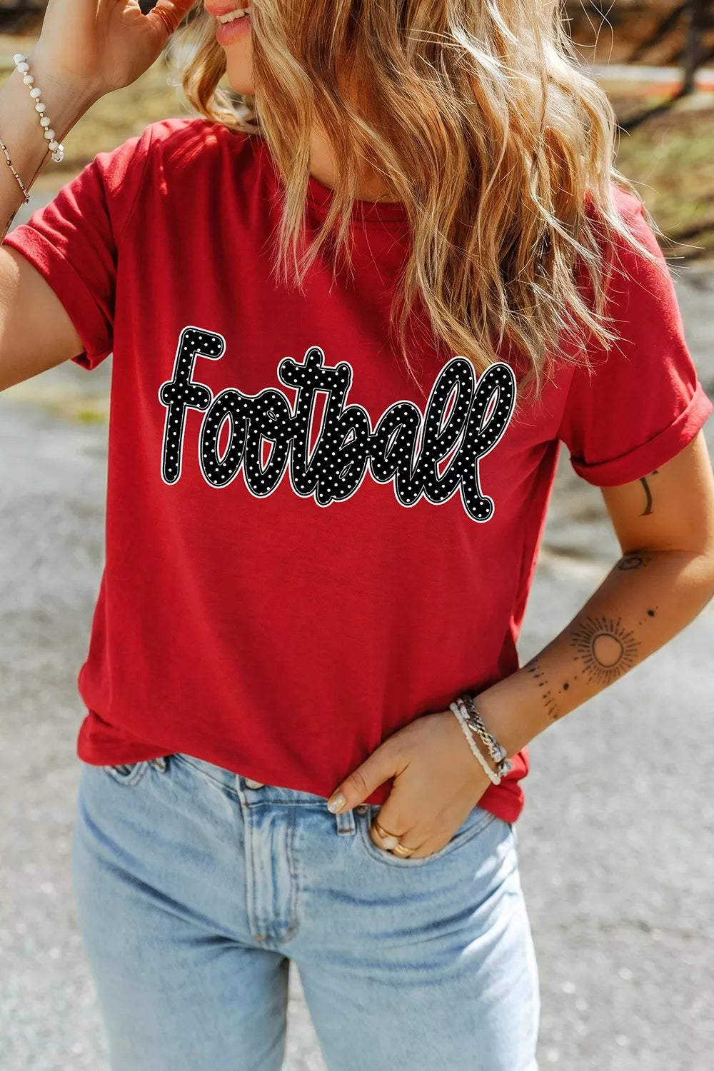 Outdoor front view of deep red game day t shirt with polka dot Football lettering and jeans